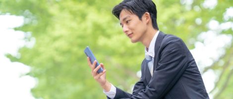 座ってスマートフォンで英語を聴く男性